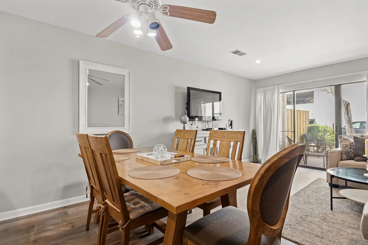A spacious interior scene featuring a wooden dining table set for a meal, a comfortable seating area with plush sofas, and large windows that flood the space with natural light. The layout shows a seamless connection between living and dining areas, with decor that invites relaxation and togetherness.