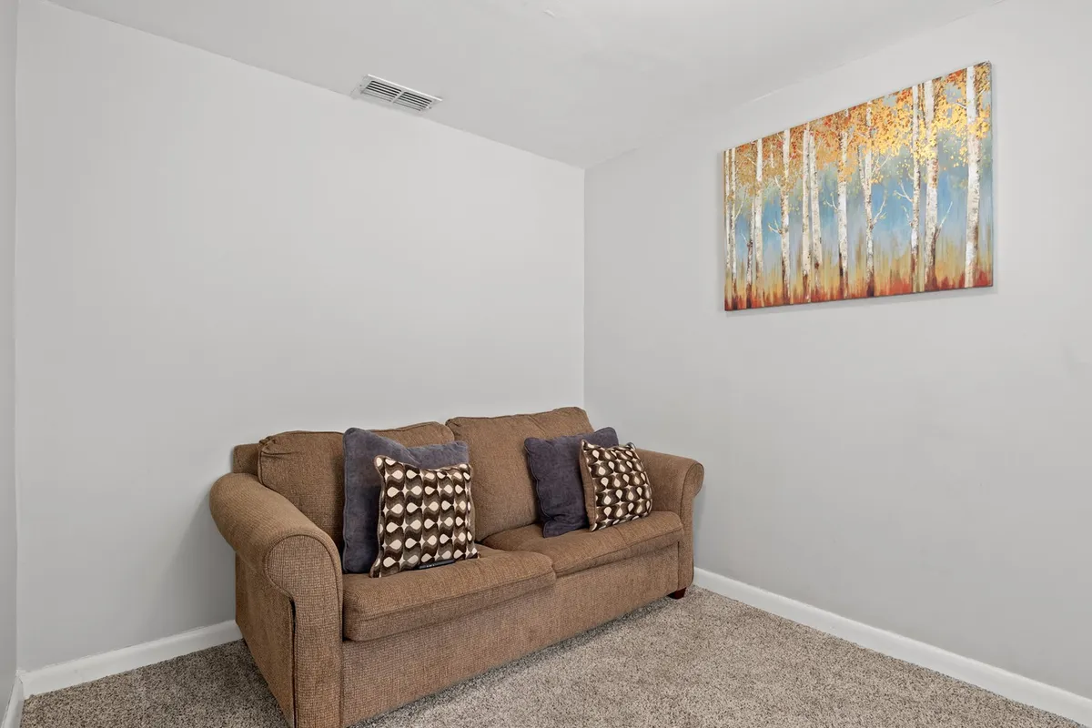 A bright and welcoming living room scene with a comfortable sofa, decorative pillows, and modern wall art. The space exudes warmth and offers a spot for relaxing or gathering with friends and family after a day out.